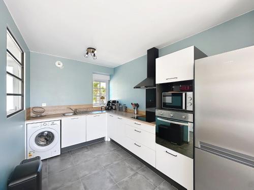 a kitchen with white cabinets and a washer and dryer at Gîtes Ti Tud-Kozh Le Guébriand et L'Arguenon in Pluduno