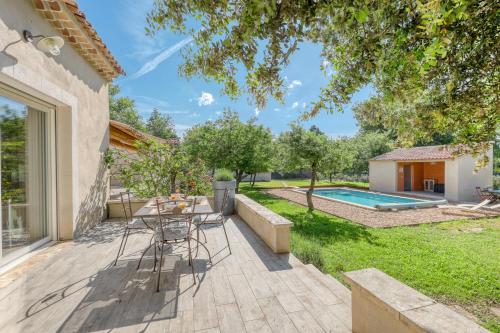 un patio avec une table et des chaises et une piscine dans l'établissement Le JARDIN DES DELIS gite NEUF avec piscine bio UV, à Saint-Saturnin-lès-Apt