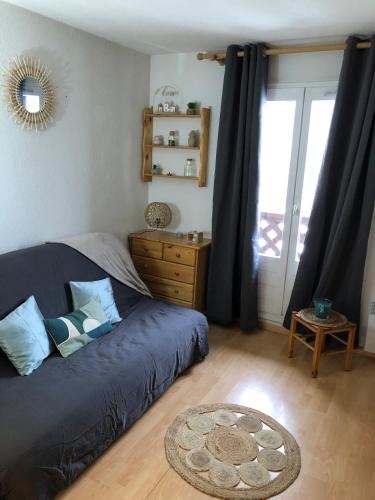a living room with a blue couch and a window at Cozy studio in La Foux