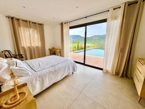 une chambre avec un lit et une vue sur une piscine dans l'établissement Villa Corian, vue sur l'Estérel et piscine chauffée, à Les Adrets-de-l'Estérel
