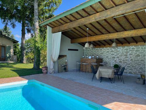 a patio with a swimming pool and a wooden pergola at Villa Simone in Arthémonay