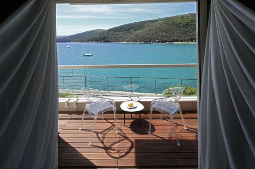 a balcony with two chairs and a table and a view of the water at Boutique Hotel Adoral in Rabac