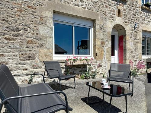 a patio with chairs and a table and a window at Gîtes Ti Tud-Kozh Le Guébriand et L'Arguenon in Pluduno