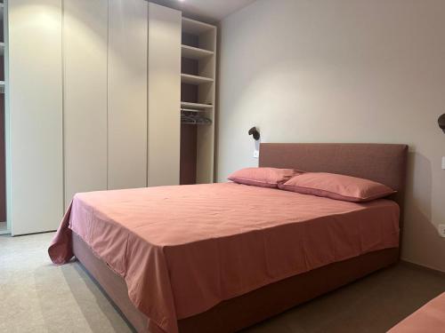 a bedroom with a large bed with pink sheets at Appartamento Toscanini in Milano Marittima