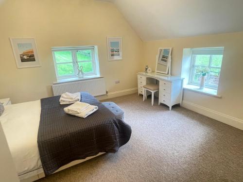 a bedroom with a bed and a desk and two windows at Rural Coastal Self-Catering Accommodation for 8, Near Sandringham Estate, Norfolk in Ingoldisthorpe