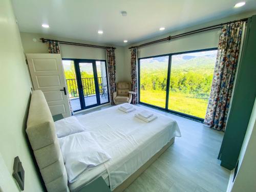 une chambre avec un lit et une grande fenêtre dans l'établissement Küre Dağları Manzaralı Şömineli ve Bahçeli Villa, à Büyükkıran