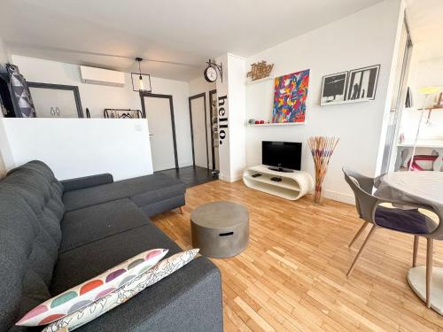 a living room with a gray couch and a tv at T3 parking and balcony eurexpo in Bron