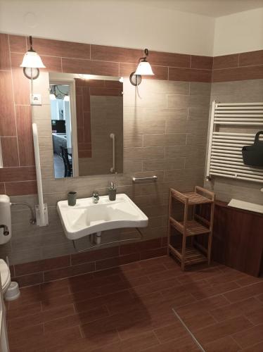 a bathroom with a sink and a mirror at Thermália Vendégházak - Levendula Apartman in Kaba