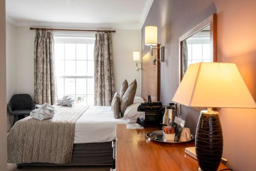 a hotel room with a bed and a desk with a lamp at Fishmore Hall Hotel and Boutique Spa in Ludlow