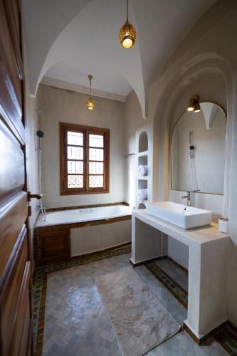 a bathroom with a tub and a sink and a mirror at Villa Dar Ambre in Marrakech
