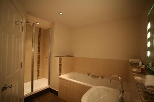 a bathroom with a tub and a shower and a sink at Fishmore Hall Hotel and Boutique Spa in Ludlow