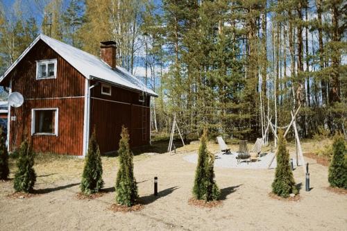 a red barn in the middle of a yard with trees at Nordic Eco Retreat with Sauna, Firepit and Slow Living in Kesälahti