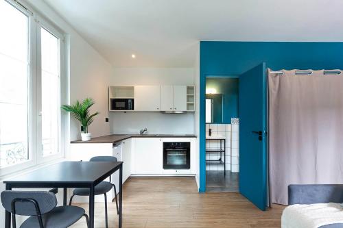 une cuisine avec une table et un mur bleu dans l'établissement Villa Maska - Studios avec Terrasse proche plage et aéroport de Nice, à Nice