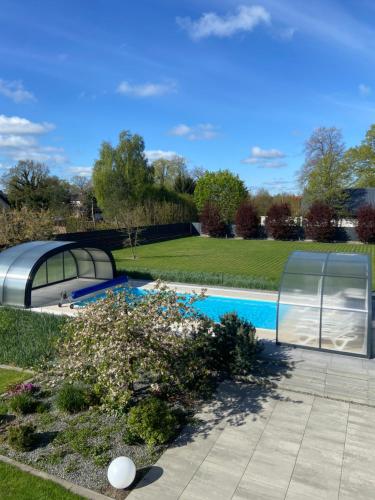 a swimming pool in a garden with a greenhouse at Apartamenty MarMar in Sławoszynko