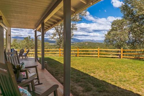 a porch with chairs and a fence with mountains in the background at Rivertop Hideaway with HUGE views-Hot Tub-EV-more! in Ahwahnee