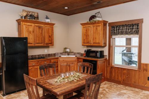 a kitchen with a wooden table and a black refrigerator at Sojourner's Lodge & Log Cabin Suites in Dundee