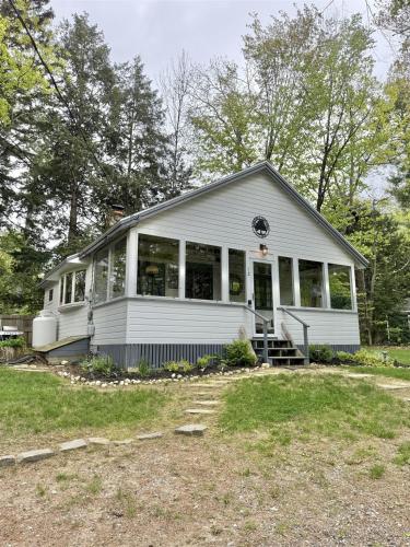 a white house with a lot of windows at KENDALL COTTAGE LIMIT 6 villa in North Sebago