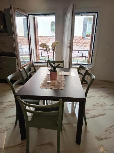 a dining room table with chairs and a vase with flowers on it at Ca lucia Canal View in Venice