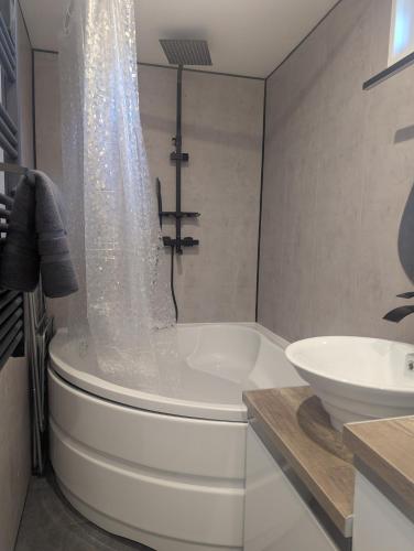 une salle de bain avec une baignoire et un lavabo dans l'établissement Le nid des voyageurs, Maison de vacances familiale, à Leyment