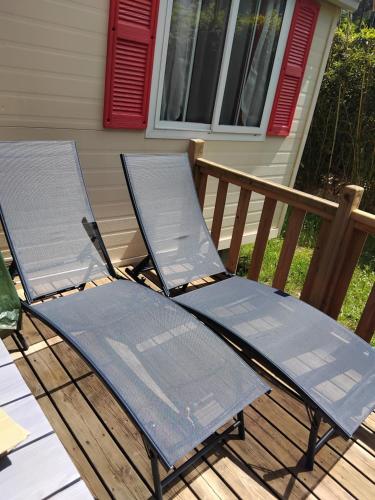 two chairs sitting on a deck in front of a house at Mobil home LE COUCOU in Le Martinet