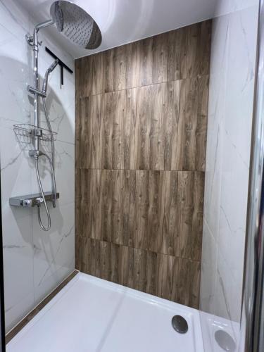 a bathroom with a shower with a wooden wall at VipStay - Stilvoll und geräumige Apartments mit Terasse oder Balkon, Küche, kostenloses Parken, WLAN, Smart Tv in Wiesloch