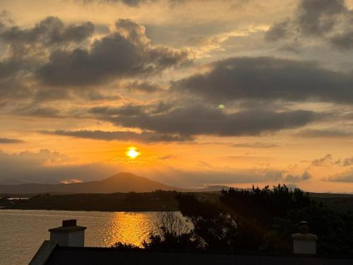 a sunset over a body of water with the sun at Tatis Bake-Away in Roundstone