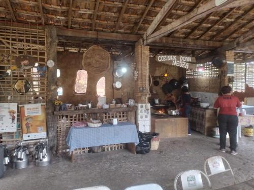 a woman standing in a kitchen with a table at Chales rota da pedra in São Bento do Sapucaí