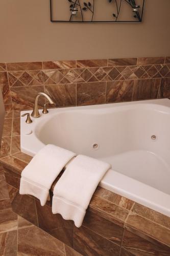 a bathroom with a bath tub with two towels at Sojourner's Lodge & Log Cabin Suites in Dundee