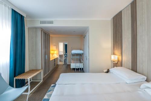a hotel room with two beds and a chair at Hotel Europa in Garda