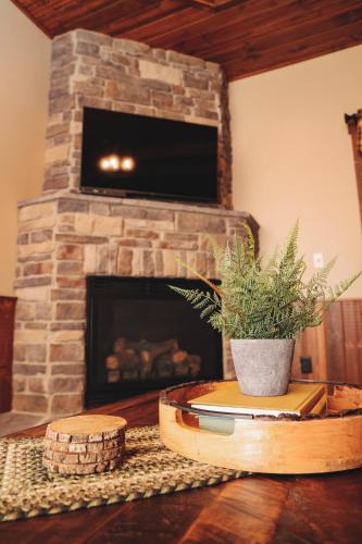 a living room with a stone fireplace with a tv at Sojourner's Lodge & Log Cabin Suites in Dundee