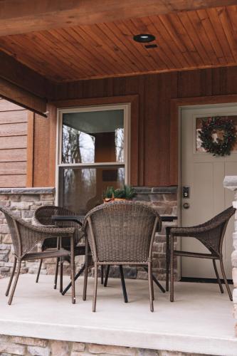 a patio with wicker chairs and a table on a porch at Sojourner's Lodge & Log Cabin Suites in Dundee