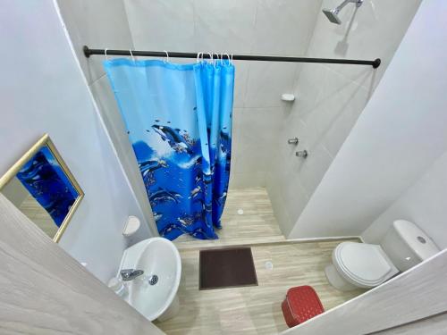 a bathroom with a blue shower curtain and a toilet at Perla del río habitaciones in Barranquilla