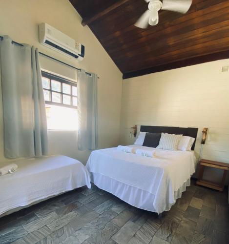 a bedroom with two beds and a window at Encanto Paraty Beach in Paraty