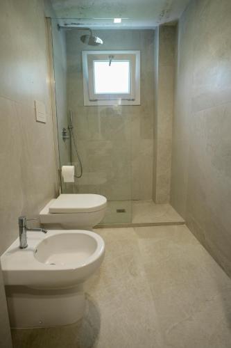 a bathroom with a toilet and a sink and a shower at Praialonga Suites with Pool and Garden in Le Castella