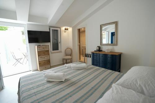 a bedroom with a bed and a dresser and a mirror at Praialonga Suites with Pool and Garden in Le Castella
