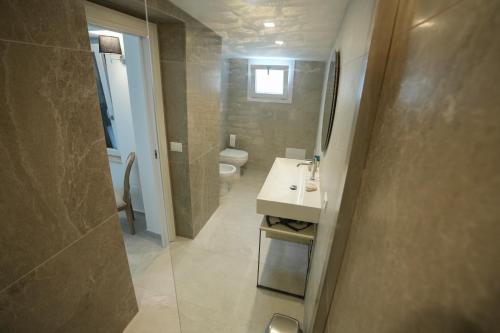 a bathroom with a sink and a toilet at Praialonga Suites with Pool and Garden in Le Castella
