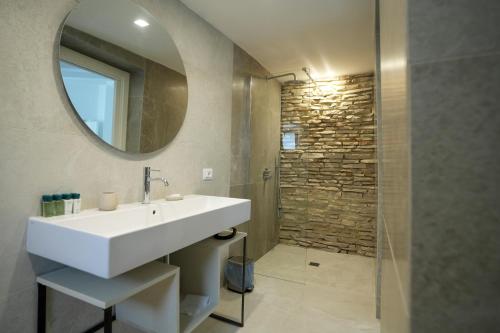 a bathroom with a sink and a mirror and a shower at Praialonga Suites with Pool and Garden in Le Castella