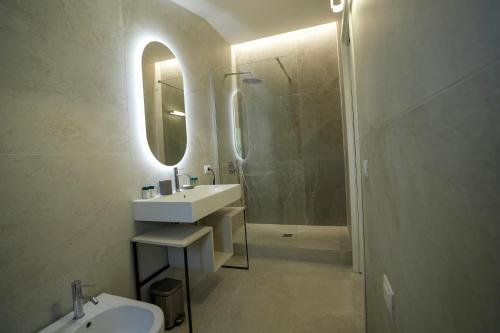 a bathroom with a sink and a mirror and a shower at Praialonga Suites with Pool and Garden in Le Castella