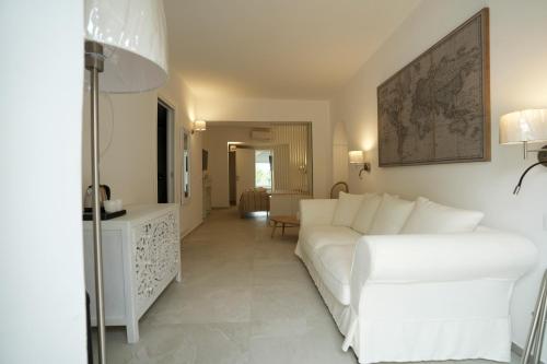 a living room with a white couch and a table at Praialonga Suites with Pool and Garden in Le Castella