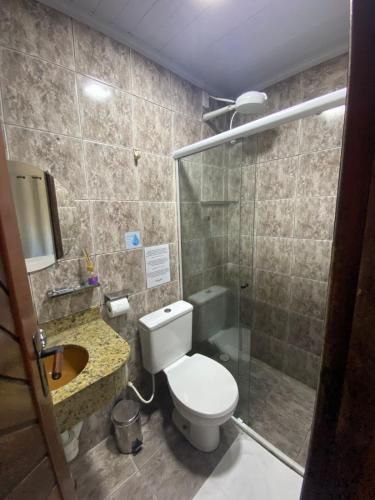 a bathroom with a toilet and a glass shower at Encanto Paraty Beach in Paraty