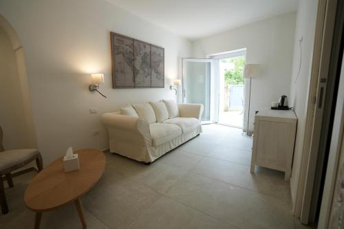 a living room with a white couch and a table at Praialonga Suites with Pool and Garden in Le Castella