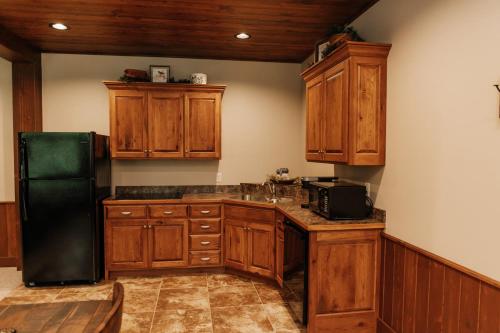 a kitchen with wooden cabinets and a black refrigerator at Sojourner's Lodge & Log Cabin Suites in Dundee