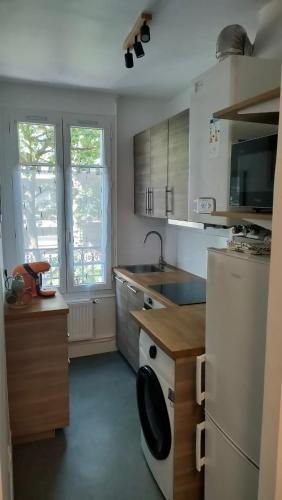 La cuisine est équipée d'un réfrigérateur blanc et d'un lave-vaisselle. dans l'établissement Boul'Bohème - 4 guests 1 bedroom 2 beds 1 bathroom, à Boulogne-Billancourt