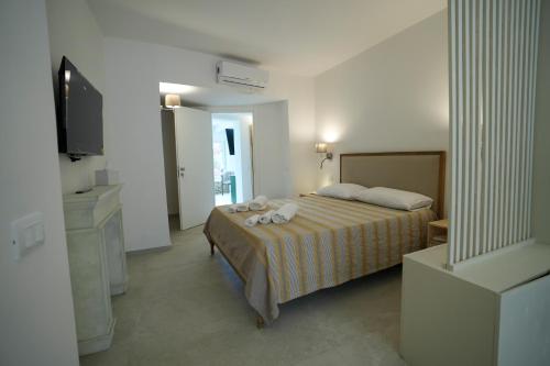 a bedroom with a bed and a flat screen tv at Praialonga Suites with Pool and Garden in Le Castella