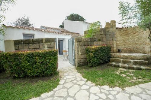 a house with a stone wall and a stone pathway at Praialonga Suites with Pool and Garden in Le Castella