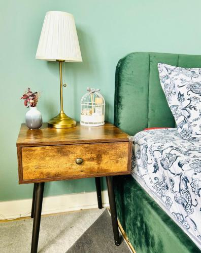 une lampe sur une table à côté d'un canapé vert dans l'établissement Un Cocon Vert Canard à côté Paris 14ème - 3 pièce de 70m2 avec 2 chambres et un grand salon lumineux, à Montrouge