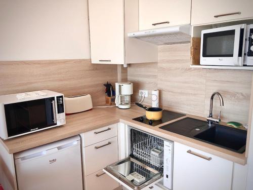 une petite cuisine avec un évier et un micro-ondes dans l'établissement Studio-alcôve lumineux en front de mer, à Neufchâtel-Hardelot