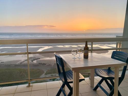 - une table avec 2 verres à vin et une bouteille de vin dans l'établissement Studio-alcôve lumineux en front de mer, à Neufchâtel-Hardelot