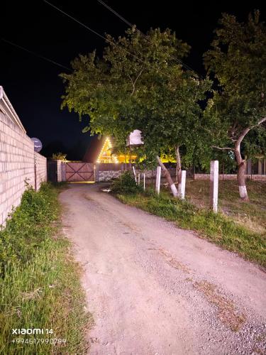 a dirt road with a fence and trees at night at Quba A-Frame near Lake & Forest in Quba