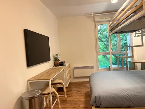 une chambre avec un lit et un bureau avec une télévision dans l'établissement Cosy Studio Disney Paris RER A, à Montévrain